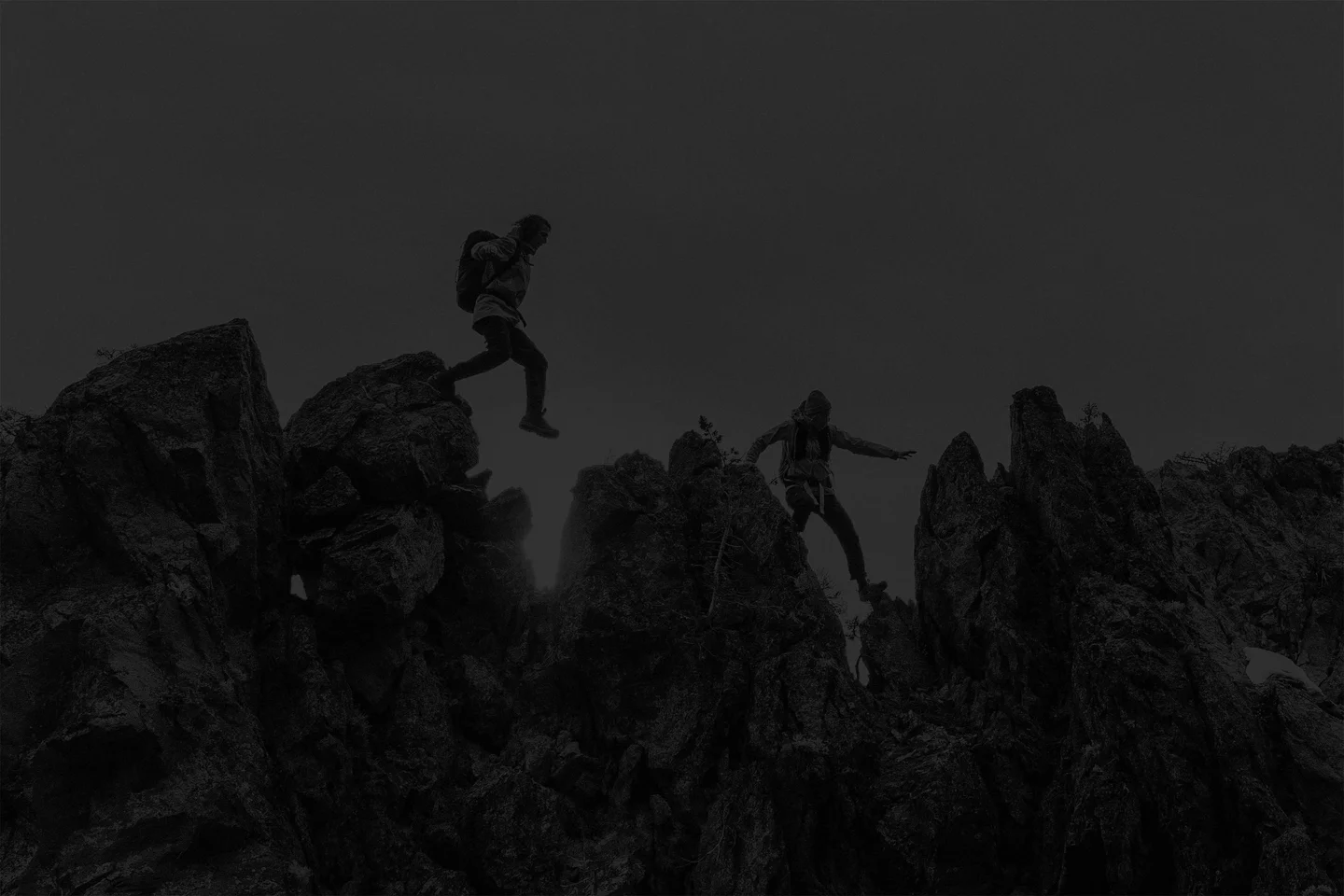 Two alpinists scale a jagged rocky ridge on their way to the summit